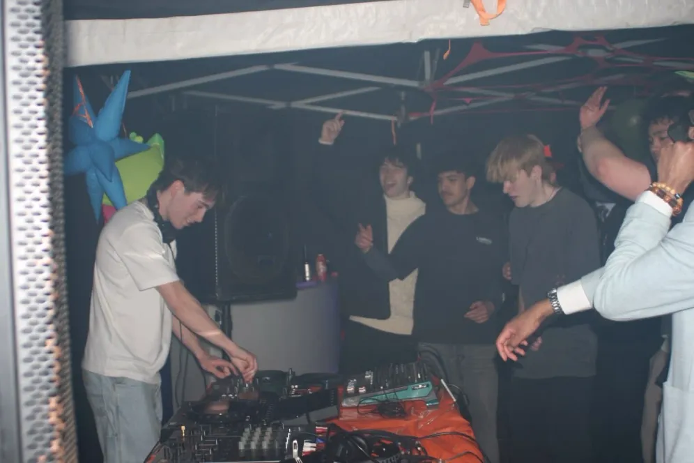 MC Cal at the decks, mixing on a controller at a party